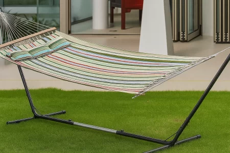 Fully assembled hammock on metal stand placed on green lawn outside a modern house.