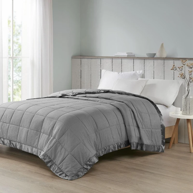 Grey quilted comforter on bed with rustic wooden headboard and white pillows.