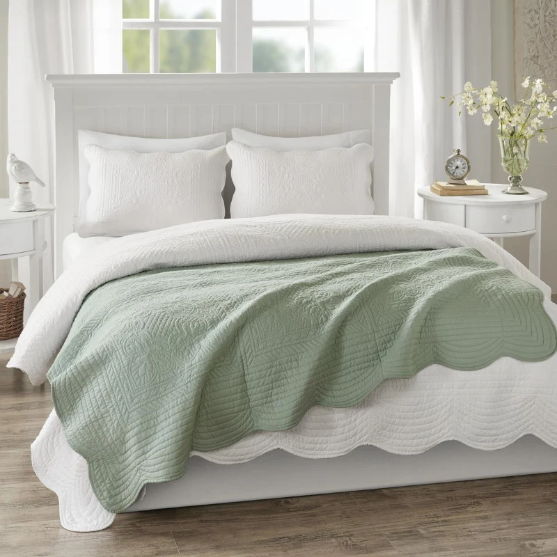 Bed with white bedding and a green throw blanket.
