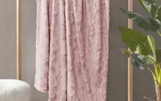 Pink faux fur blanket hanging on a rack.