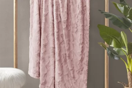 Pink faux fur blanket hanging on a rack.