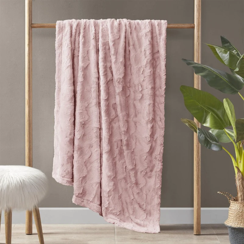 Pink faux fur blanket hanging on a rack.