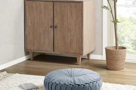 Blue round floor cushion placed on cream shaggy rug near cabinet.