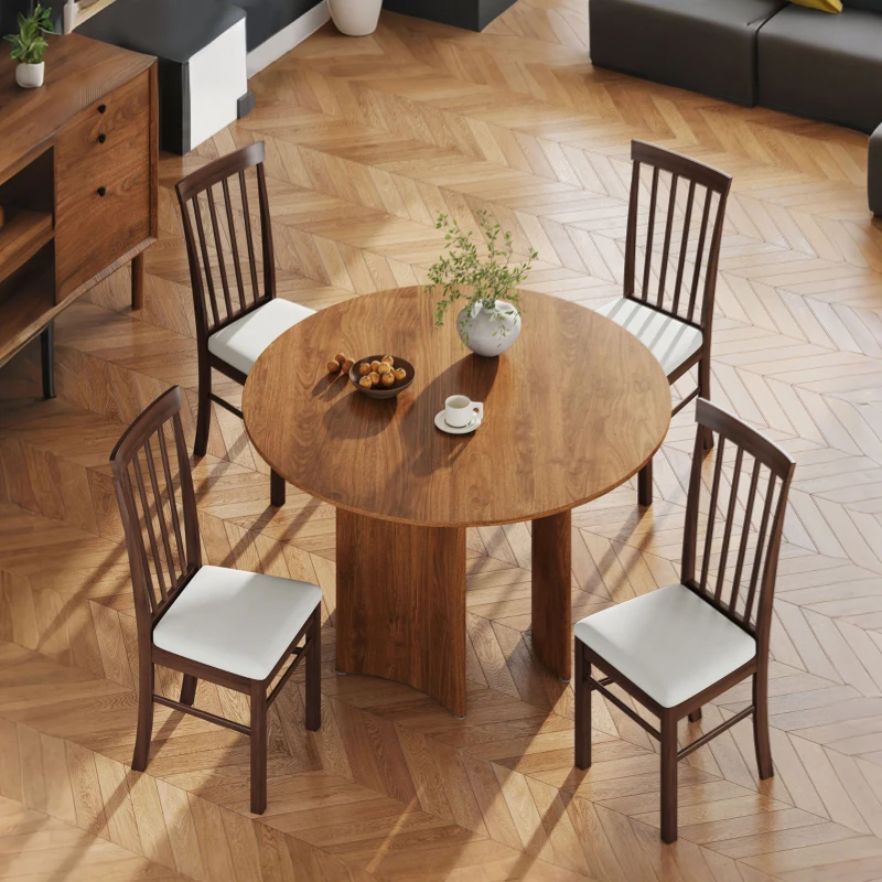 Classic round wood dining table paired with four slatted-back chairs featuring white padded seats in a herringbone floor room.