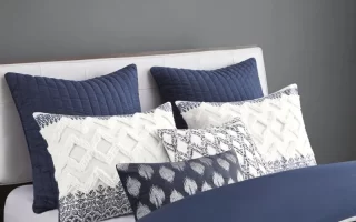 White and blue decorative pillows neatly arranged on bed