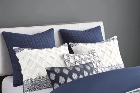 White and blue decorative pillows neatly arranged on bed