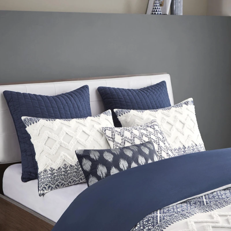 White and blue decorative pillows neatly arranged on bed