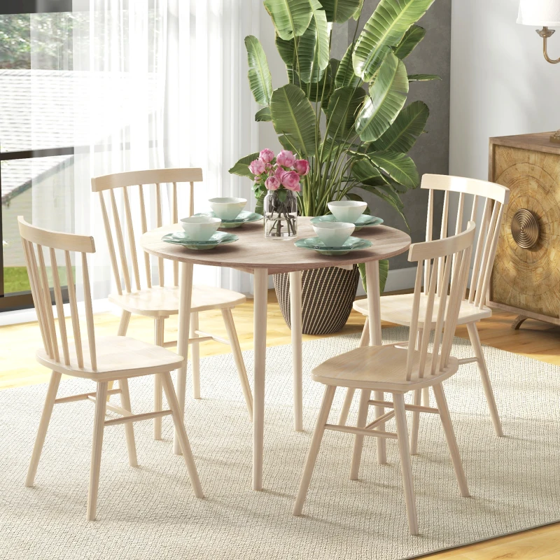 Light wood round dining table with matching wooden chairs and tableware.