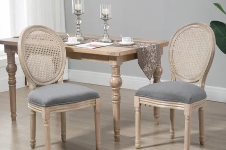 Natural wood oval-back dining chairs with grey cushions around a rustic farmhouse table in a bright dining room.