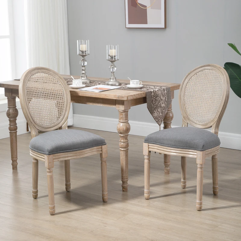 Natural wood oval-back dining chairs with grey cushions around a rustic farmhouse table in a bright dining room.