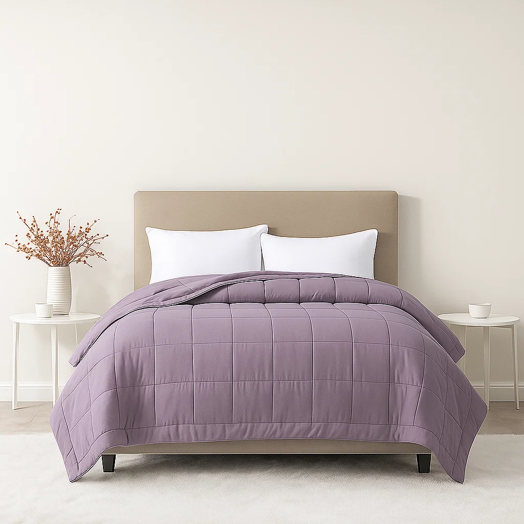 Lavender quilted comforter on bed with beige headboard and white pillows.