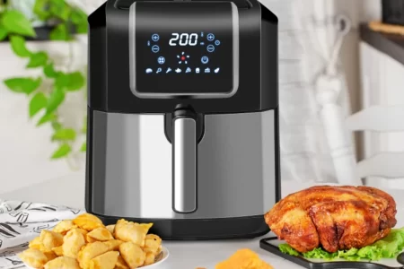 Modern air fryer with fried chicken and snacks on table.