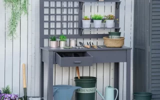 Gray potting bench with shelves, plants, and gardening tools.