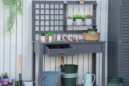 Gray potting bench with shelves, plants, and gardening tools.