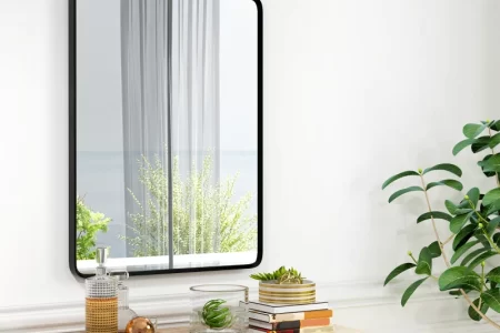 Wall-mounted rectangular mirror above a dresser with books and décor.