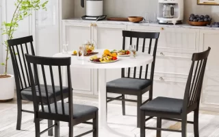 Black dining chairs around a white round table.