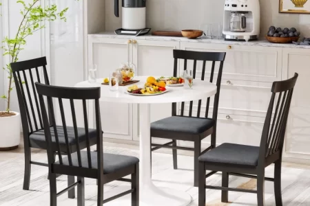 Black dining chairs around a white round table.