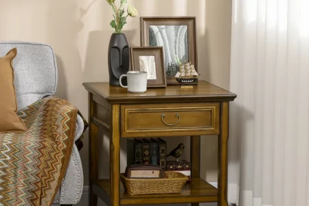 Wooden end table styled with decor, books, and framed photos.