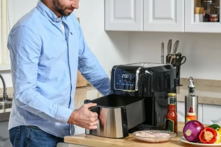 Man preparing to cook food in an air fryer on a kitchen counter.