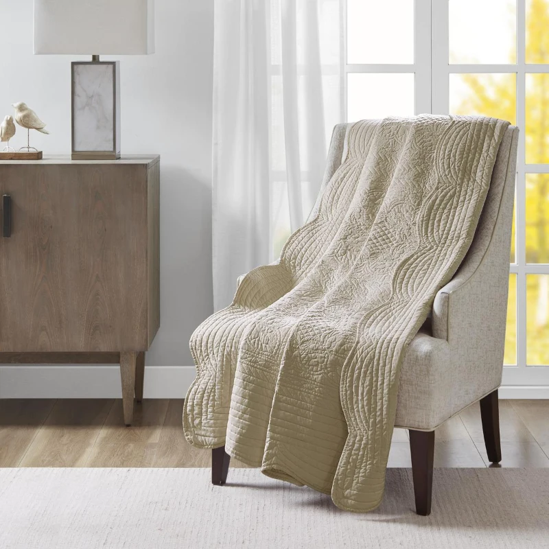 Beige quilt draped over a chair by window.