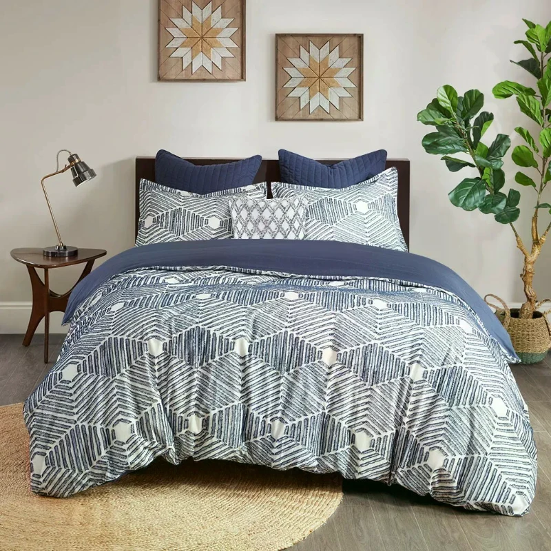 Bedroom with geometric navy and white bedding, pillows, and indoor plant.