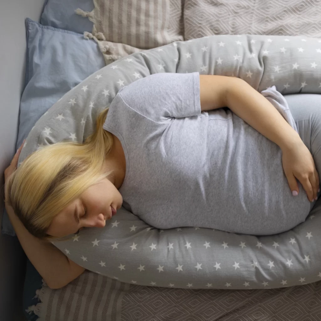 Pregnant woman sleeping comfortably with body pillow.
