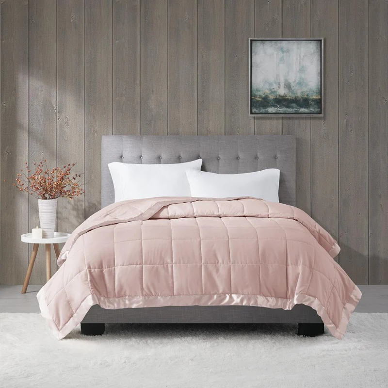Soft pink quilted comforter on bed with grey headboard and white pillows.