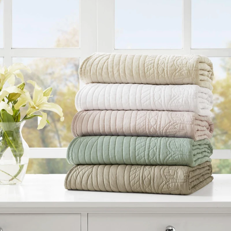 Soft pastel quilted blankets stacked on a shelf.