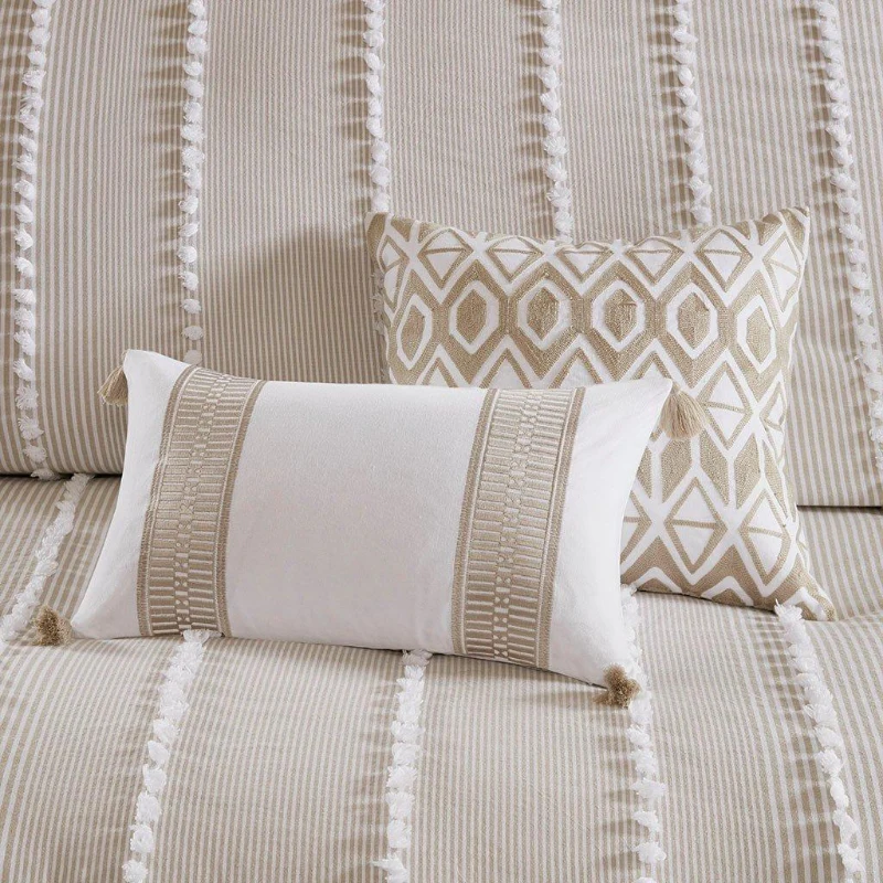 Beige and white decorative pillows on striped bedding