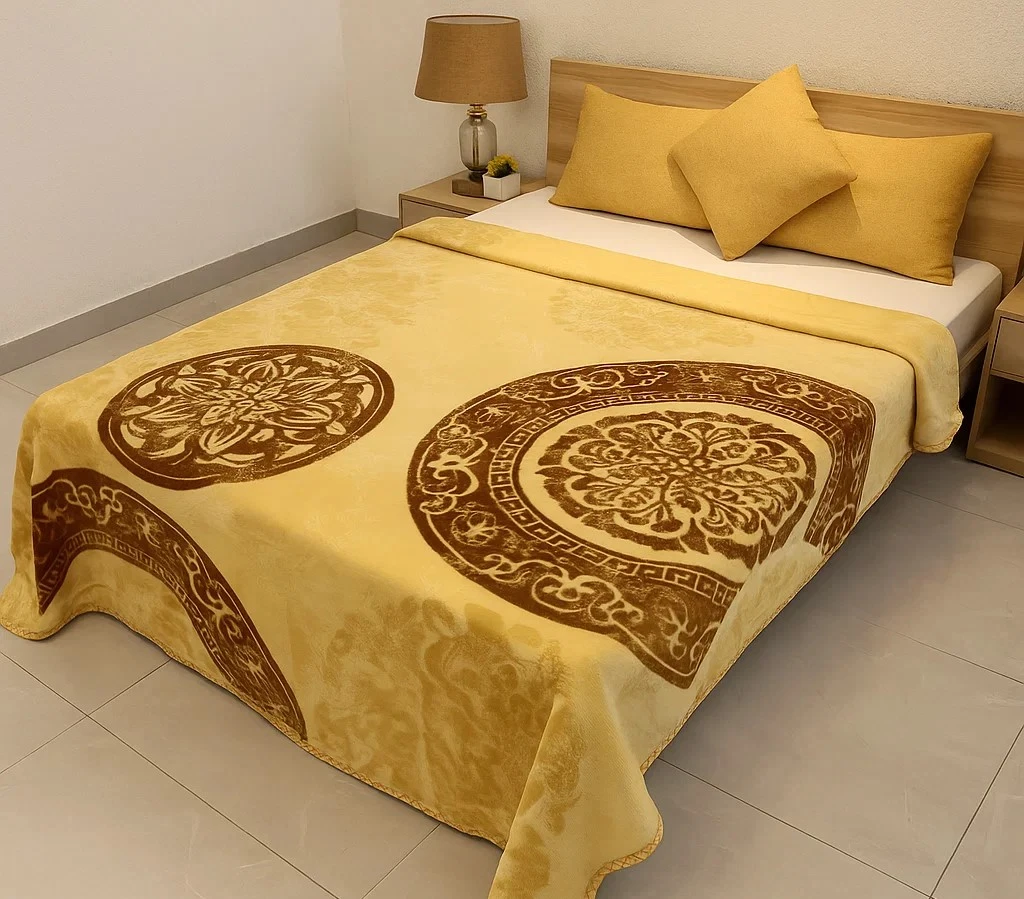 Yellow and brown printed blanket on bed with matching pillows.