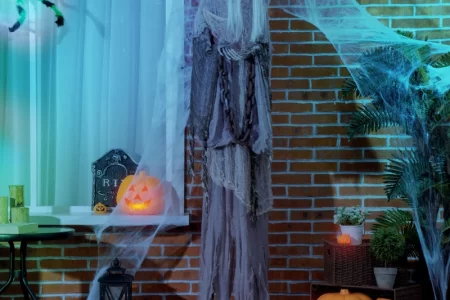 Spooky ghost figure with glowing eyes beside pumpkins outdoors.