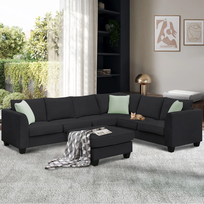 Black sectional sofa with ottoman and green accent pillows
