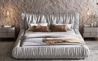 Modern upholstered bed with pillows, blanket, and nightstands.