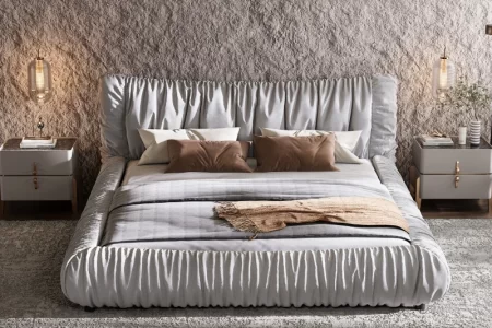 Modern upholstered bed with pillows, blanket, and nightstands.