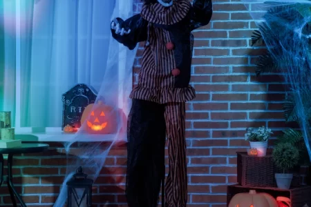 Scary clown prop with glowing eyes and cobweb decorations.
