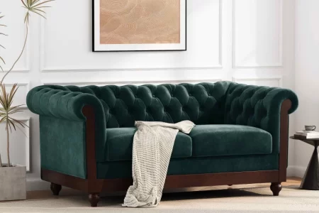 Green velvet sofa in modern living room with wall art.