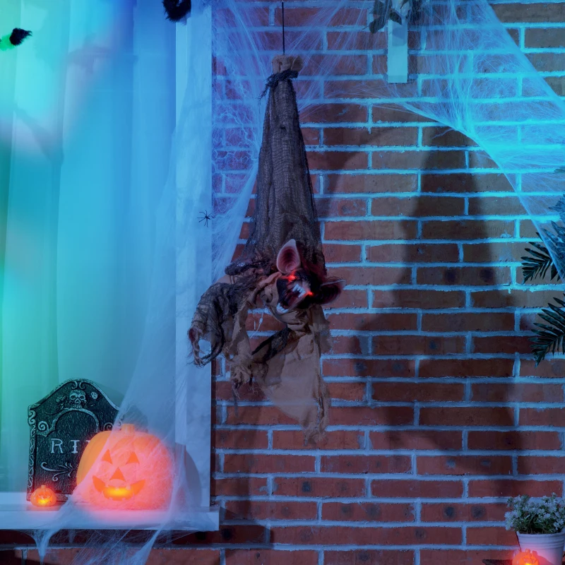 Creepy bat prop hanging outdoors with cobwebs and pumpkin lights.