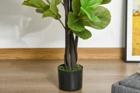 Tall faux tree in black nursery pot beside wall and framed art on wooden floor.