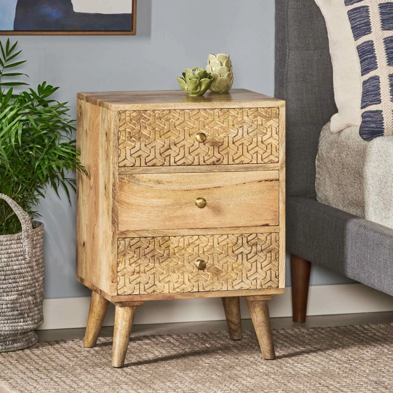 Wooden three-drawer bedside table placed beside bed with plant decor.