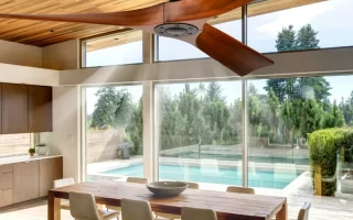 Contemporary silver ceiling fan with integrated LED light brightening an open-concept living and dining room.