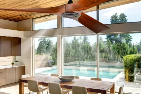 Contemporary silver ceiling fan with integrated LED light brightening an open-concept living and dining room.