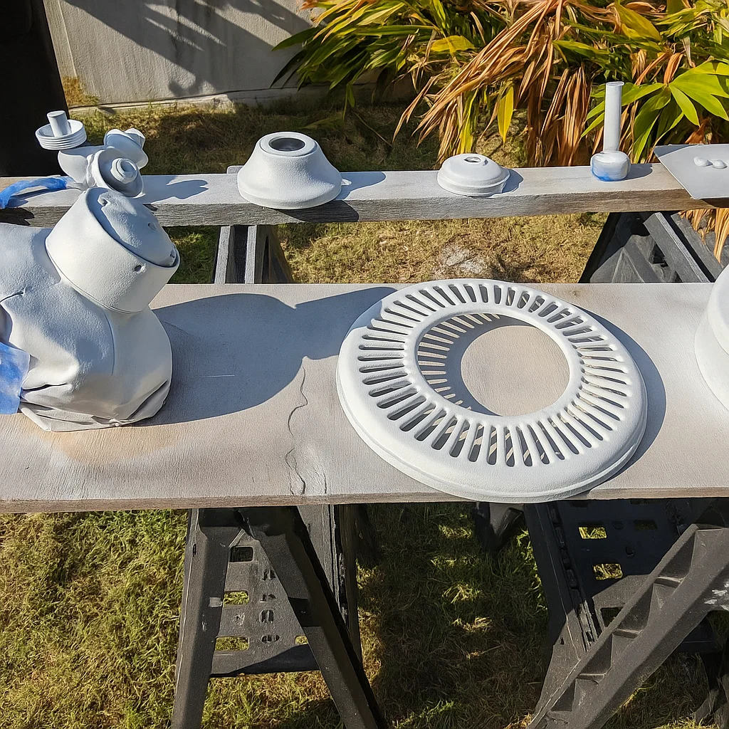 Ceiling fan parts laid out on workbench, coated with white primer