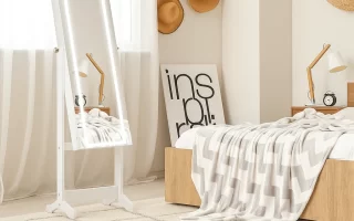 White framed LED standing mirror in bright bedroom corner.
