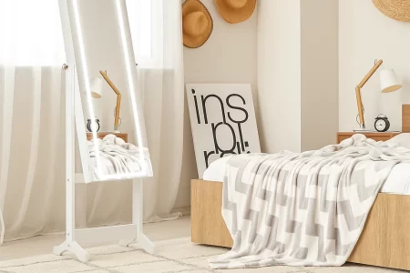 White framed LED standing mirror in bright bedroom corner.