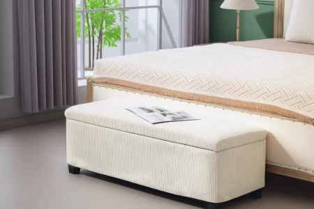 Cream storage ottoman placed at bed foot in modern minimalist bedroom