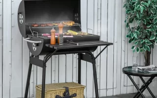 Black charcoal grill with food cooking outdoors beside table.