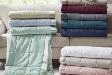 Folded colorful blankets neatly stacked on a beige sofa in a bright living room.
