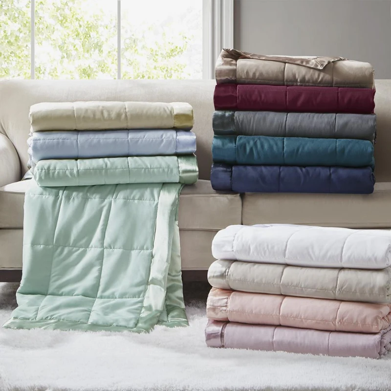 Folded colorful blankets neatly stacked on a beige sofa in a bright living room.