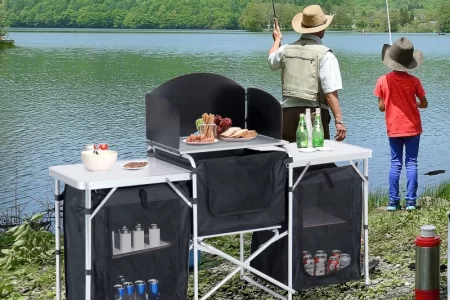 Two people fishing near a camping table setup.