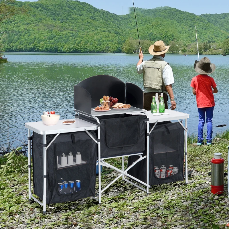 Two people fishing near a camping table setup.